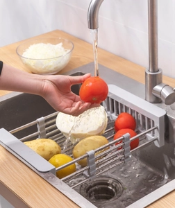 Close-up of extendable stainless steel drain rack rinsing fresh tomatoes in a kitchen sink