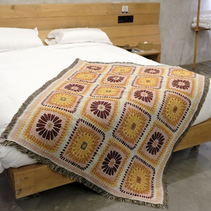 Bohemian style knitted picnic blanket with floral patterns and tassels on a bed
