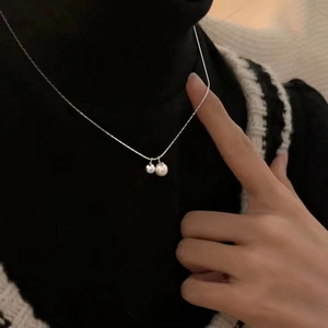 Minimalist s925 silver necklace with a freshwater pearl and silver ball on a black sweater