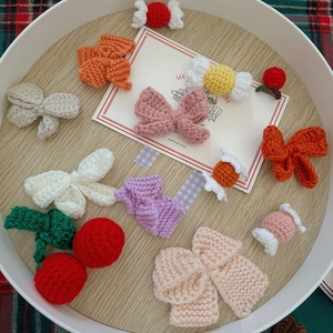 Handmade knitted Christmas DIY charms with bowknots and cherries on a festive tray