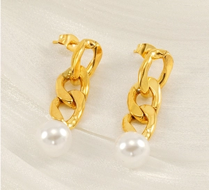 Macro detail of 18K gold-plated Cuban chain earrings with round white pearls on silk background