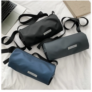 Trois sacs de sport cylindriques en noir gris et bleu sur un décor minimaliste moderne