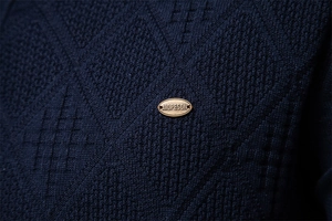 Macro detail of navy diamond pattern knit fabric with AIOPESON brand metal emblem