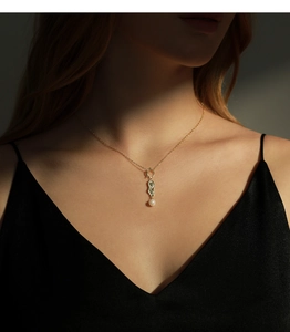 Close-up of gold irregular pendant necklace with white pearl on elegant female model