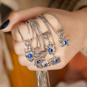 Silver box chain necklaces with butterfly and animal pendants featuring blue evil eye beads