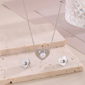 Detailed view of heart-shaped pearl necklace and earrings set on a textured stone surface
