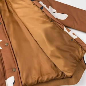 Detail der braunen Bomberjacke mit glattem Futter, Metalldruckknöpfen und Rippbündchen