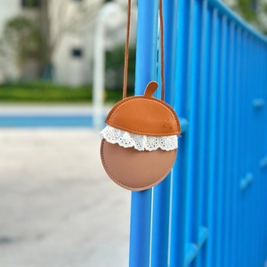 Detail view of acorn-shaped kids bag with lace trim and brown PU leather texture
