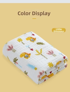 Close-up of soft cotton baby swaddle with yellow dinosaur and palm tree patterns