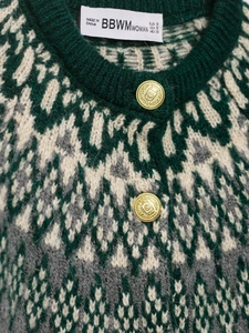 Detail of vintage geometric jacquard knit cardigan with ornate gold embossed buttons