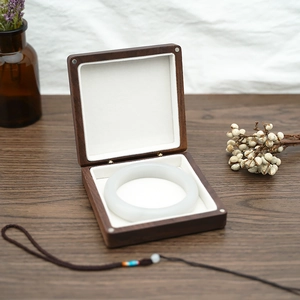 Detail of dark brown solid wood jewelry box with white velvet lining holding a jade bangle