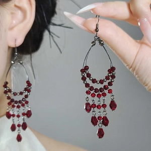 Detailed close-up of dark red glass bead fringe earrings with elegant metallic droplets