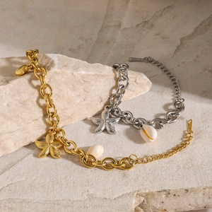 Detail of 18k gold and silver ocean charm bracelets with starfish and shells on stones