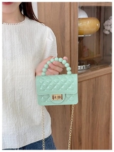 Detail of mint green quilted jelly bag with beaded handle and golden chain strap