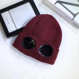 Detailed close-up of dark red cable knit beanie featuring integrated black ski goggles