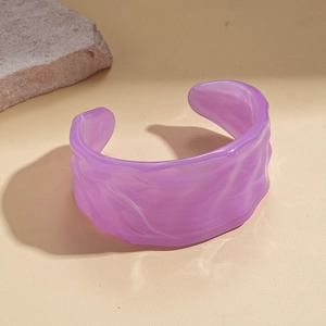 Close-up of purple acrylic cuff bracelet with wavy texture and marble effect on stone