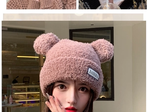 Close-up of pink plush knit hat with pom-poms and soft faux shearling texture