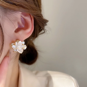 Close-up of pearl flower earring with gold trim and mother-of-pearl finish texture