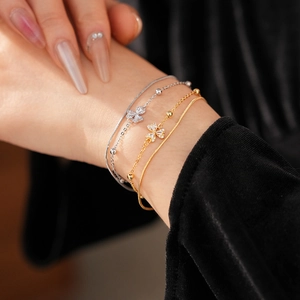 Detailansicht goldener und silberner Kleeblatt-Armbänder mit Zirkonia-Besatz am Handgelenk