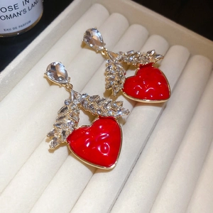 Détail de boucles d'oreilles cœur en résine rouge avec cristaux en forme d'épi de blé