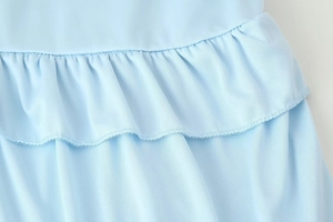 Detailed view of light blue ruffled edge and fine stitching on a V-neck top