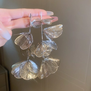 Detail of silver hollowed flower tassel earrings showing the metallic brushed finish
