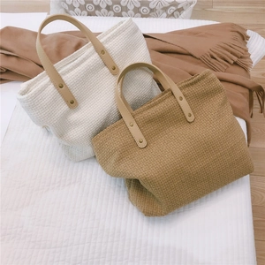 Close-up of beige woven fabric texture and brown leather handle with metal rivets