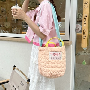 Vue détaillée de la texture matelassée et des bretelles sur le sac seau rose pastel
