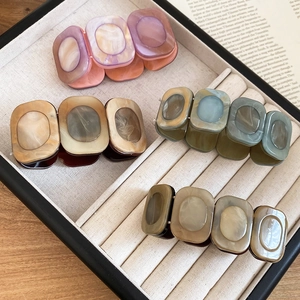 Detail of square resin bracelets with marble texture on a beige jewelry display tray