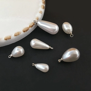 Waterdrop imitation pearl pendants in various sizes with silver metal rings on black background