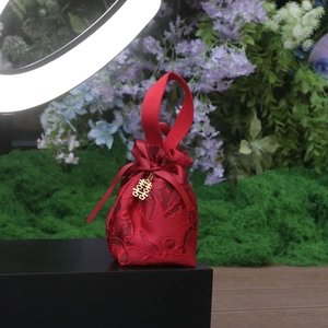 Close-up of red brocade wedding favor bag with gold Double Happiness charm and ribbon