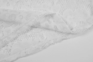 Detailed close-up of white floral lace fabric with intricate crochet patterns on the dress