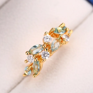 Macro shot of gold leaf ring with blue marquise gems and zircons on velvet