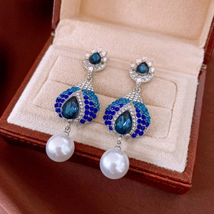 Detail of luxury waterdrop earrings with blue rhinestones and dangling white pearls