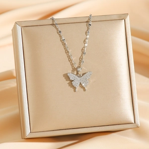 Collier avec pendentif papillon en zircon et acier titane argenté sur fond de soie