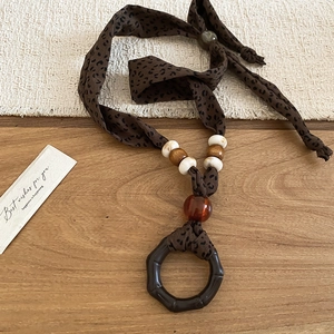 Close-up of leopard print fabric necklace with wooden beads and a brown resin pendant