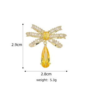 Detailed view of a gold bow brooch with clear zircon and a yellow pear-cut drop stone