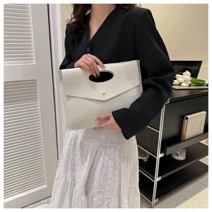 Detail of white crocodile texture envelope clutch with unique oval handle and gold buckle