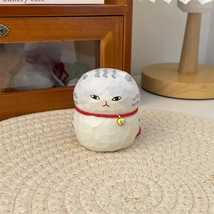 Detailed view of hand-carved style cat figurine with wood grain texture and small bell