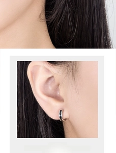 Close-up of minimalist black and silver enamel hoop earring worn on a model ear