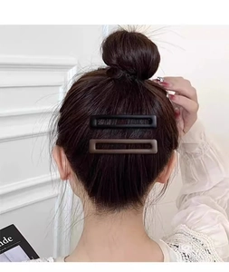 Gros plan de barrettes rectangulaires mates noires et marron portées sur les cheveux