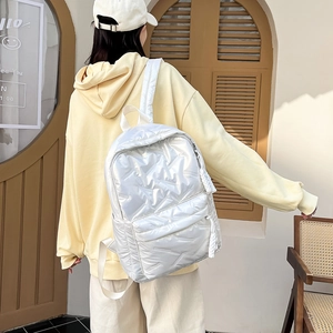 Detail eines weißen gesteppten Rucksacks mit Glanzeffekt und Daunen-Optik im Freien