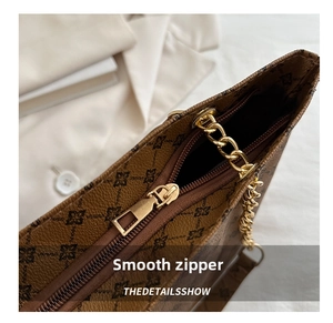 Close-up of golden zipper and brown printed pebble leather on chain shoulder bag