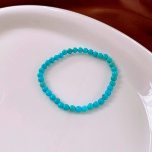 Close-up of 4mm turquoise beaded bracelet with natural textures in white ceramic tray