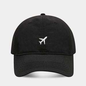 Detailed view of white airplane embroidery on a black breathable outdoor baseball cap