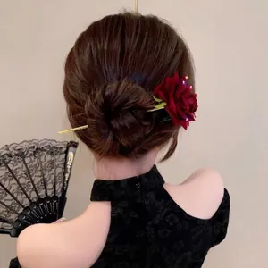Elegant red silk rose hair pin with golden leaves on traditional low bun hairstyle