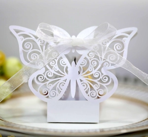Detail of laser-cut white butterfly candy box with elegant scrollwork and white silk ribbon