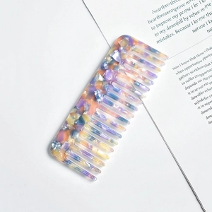 Detailed close-up of a wide-tooth acetate comb with a purple marbled pattern on a white base
