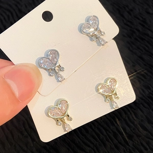 Macro detail of silver and gold heart stud earrings with sparkling rhinestone inlay