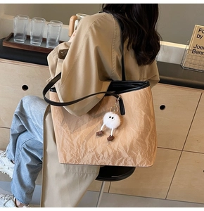 Dettaglio borsa tote stropicciata marrone con tracolla nera e ciondolo di peluche